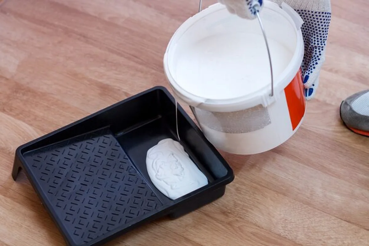 Mężczyzna wlewa białą farbę do kuwety