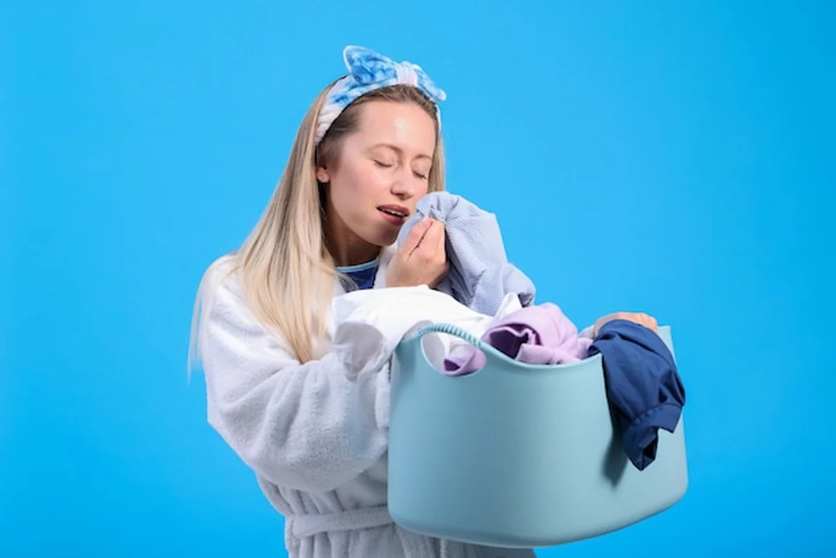 Zrelaksowana kobieta trzyma miskę świeżo wyjętej czystej bielizny z pachnącymi ubraniami