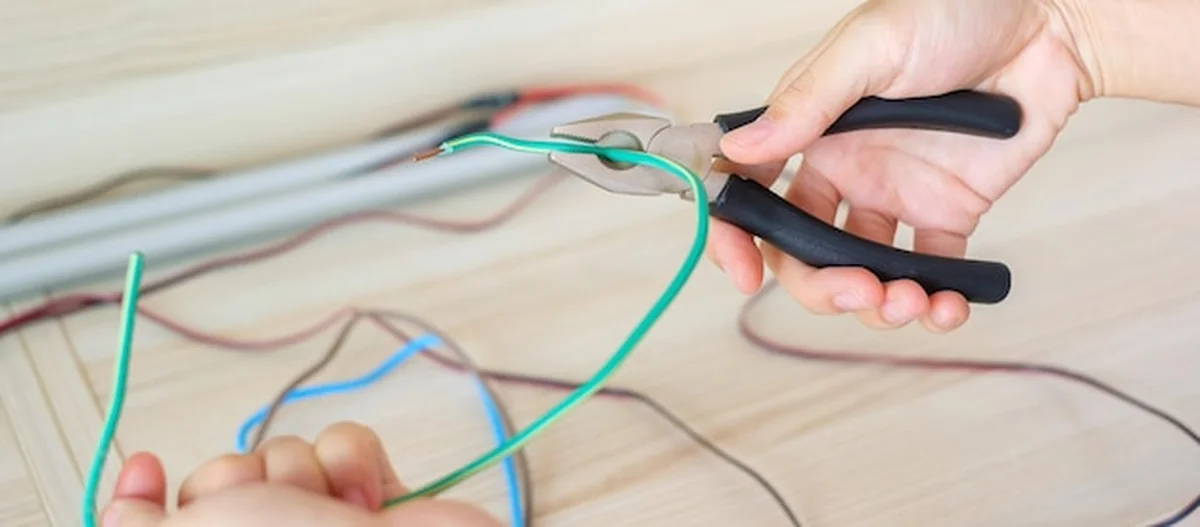 Elektryk przecina przewody elektryczne za pomocą szczypców