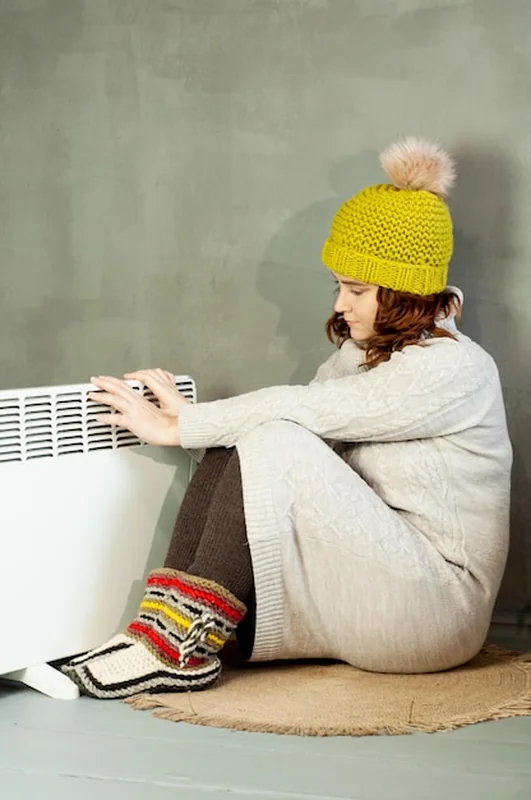 Dziewczyna ogrzewa ręce w pobliżu grzejnika w mroźną zimę