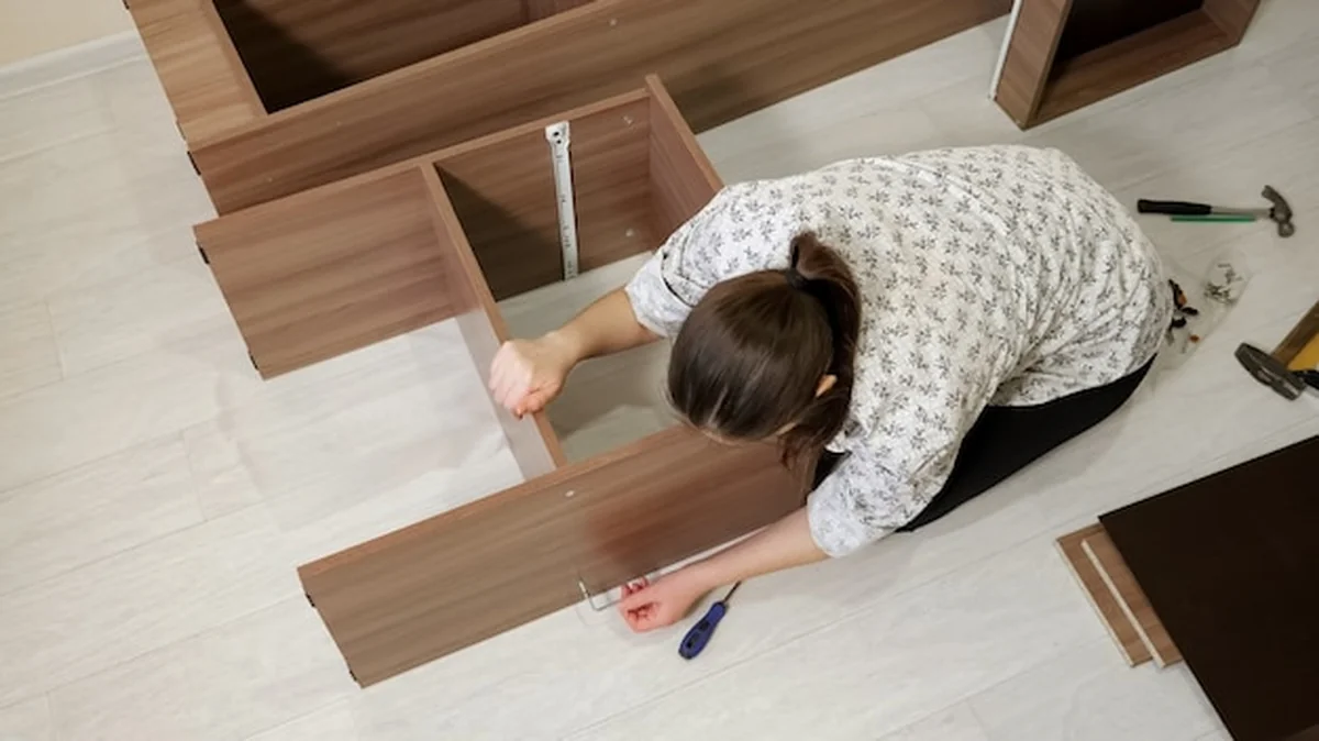 Kobieta montuje narzędzie do szafki na podłodze