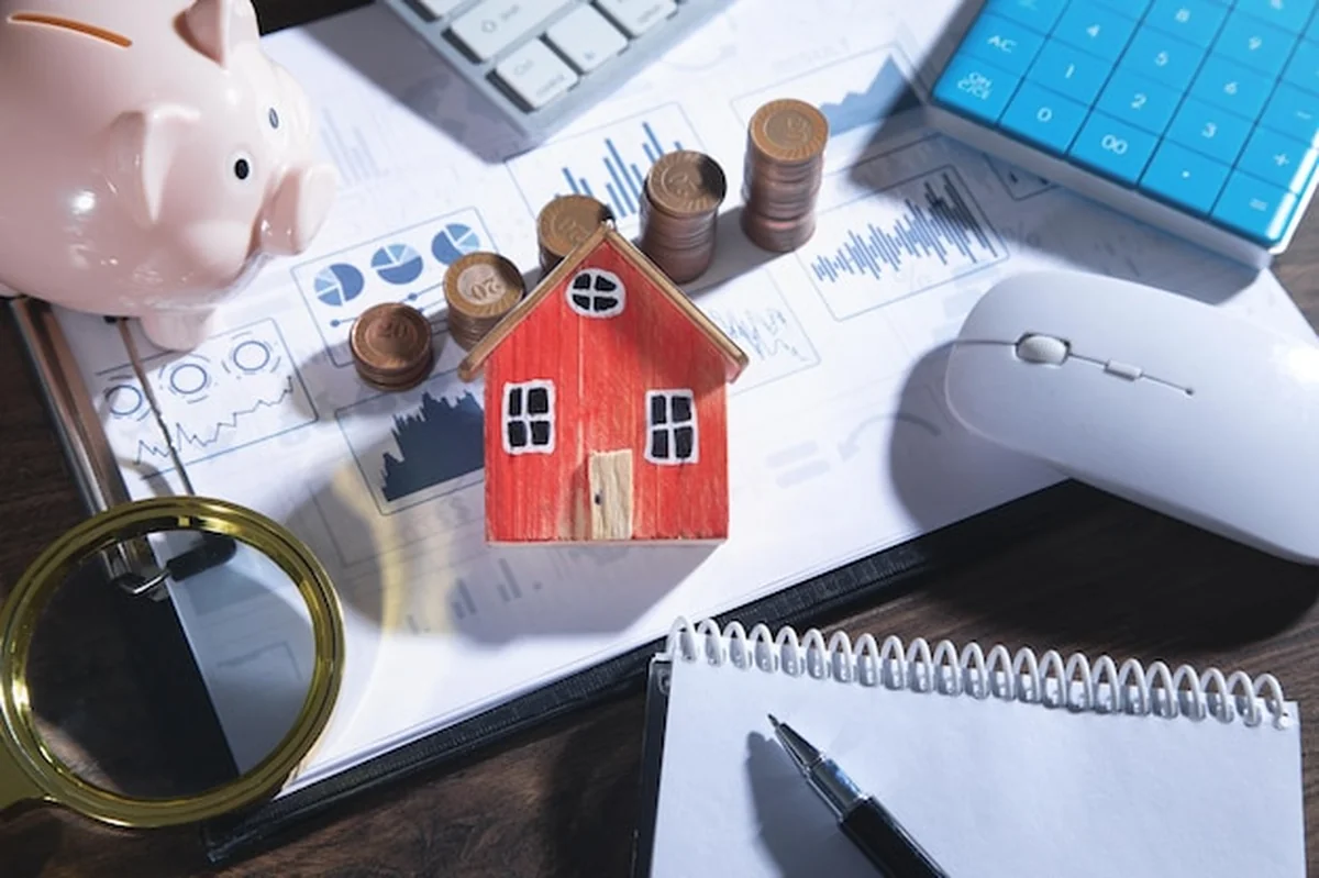 Model domu, wykresy i monety z obiektami biznesowymi na stole