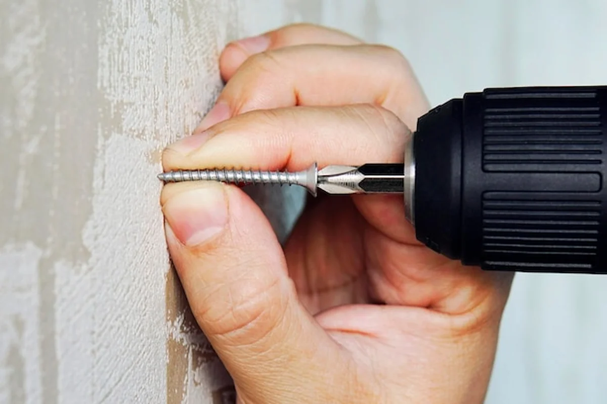 Robotnik przykręca wkręt do płyt gipsowo-kartonowych w mieszkaniu