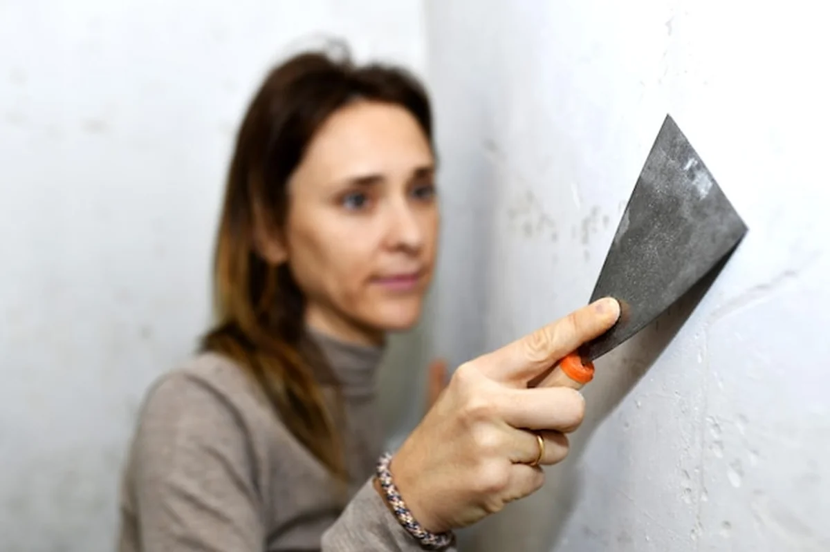 Kobieta czyści ścianę przed malowaniem w starym domu