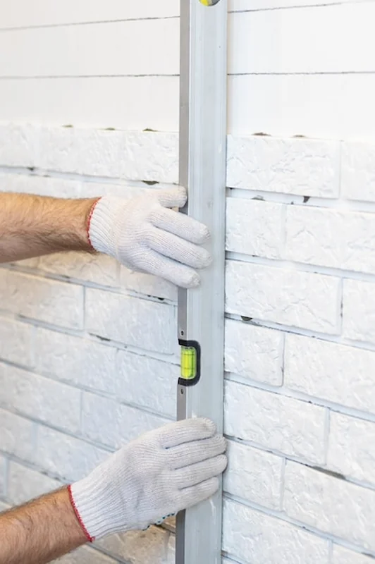 Budowniczy montuje cegłę dekoracyjną na płaskiej ścianie