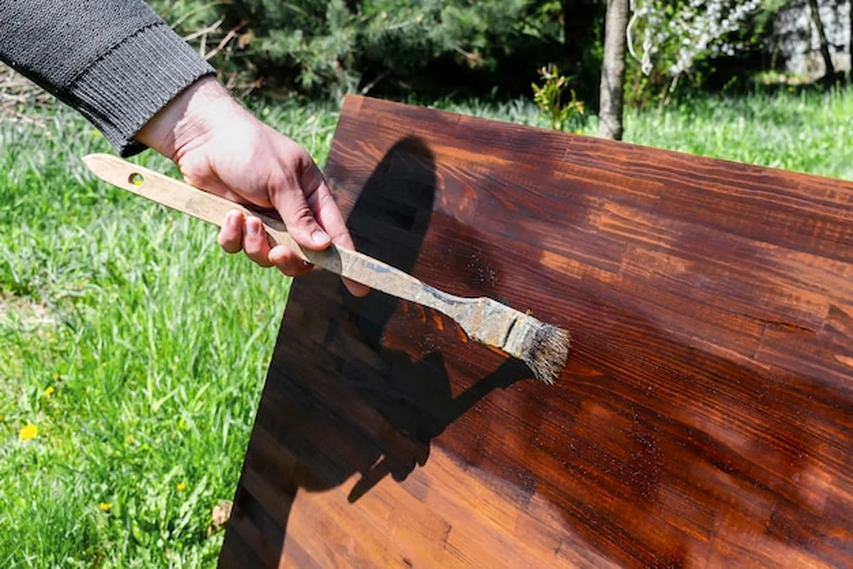 Mężczyzna malujący drewno brązową plamą na stole