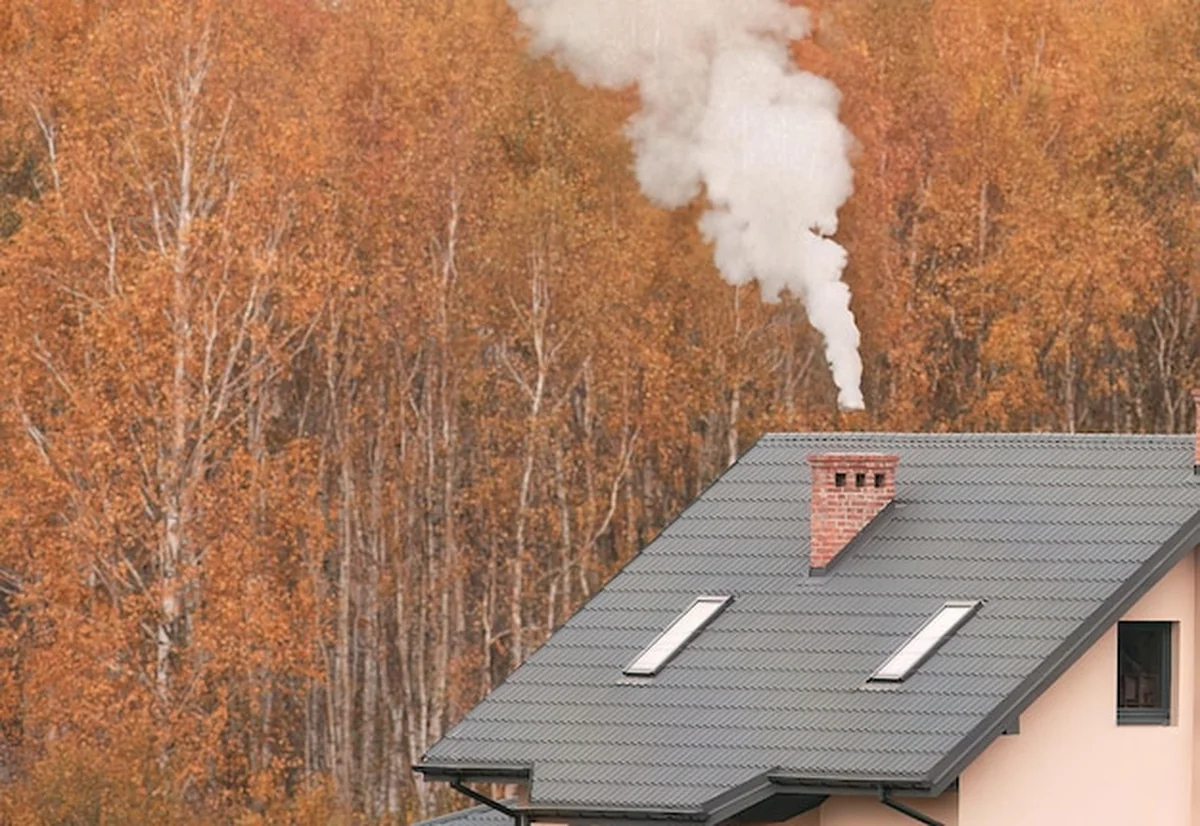 Dom z dymem wydobywającym się z komina pośród złotych drzew, szary dach i trzy okna