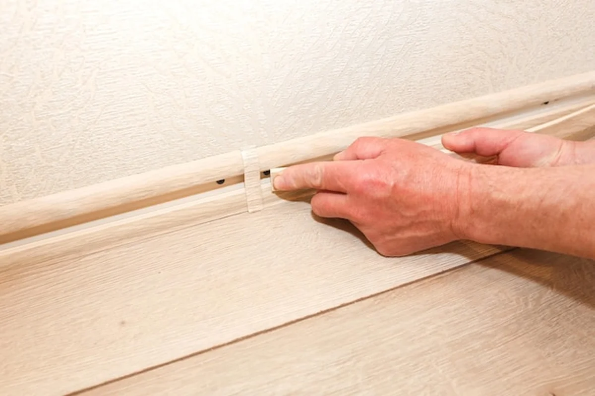 Mężczyzna montuje listwę przypodłogową podczas remontu mieszkania