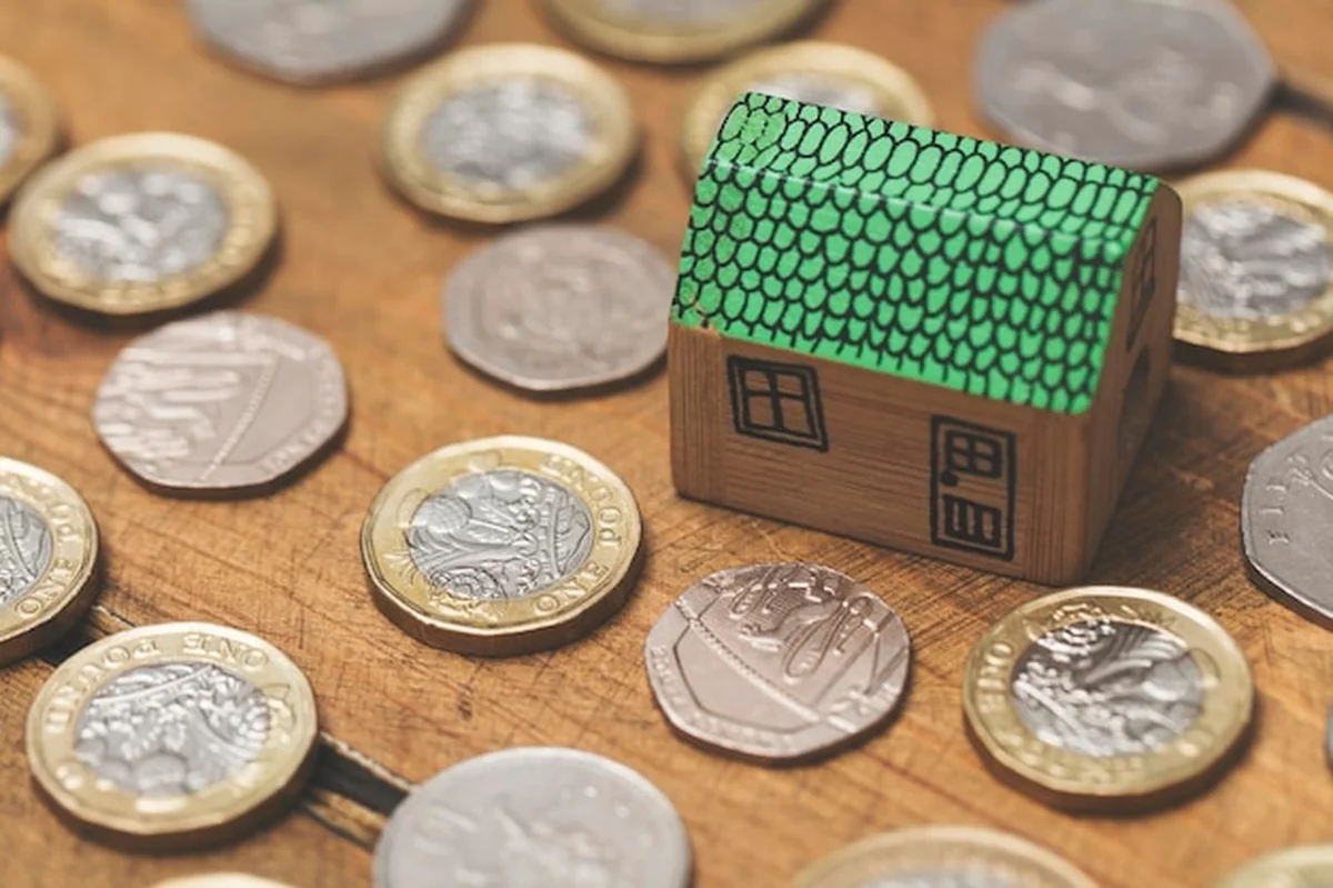 Model domu z monetami na tle białego tła