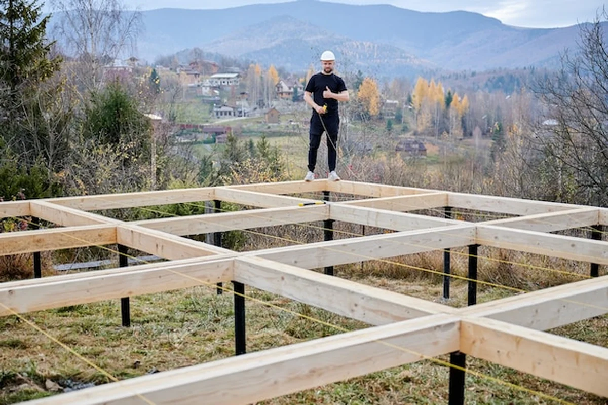 Pracownik budujący drewniany dom na fundamencie