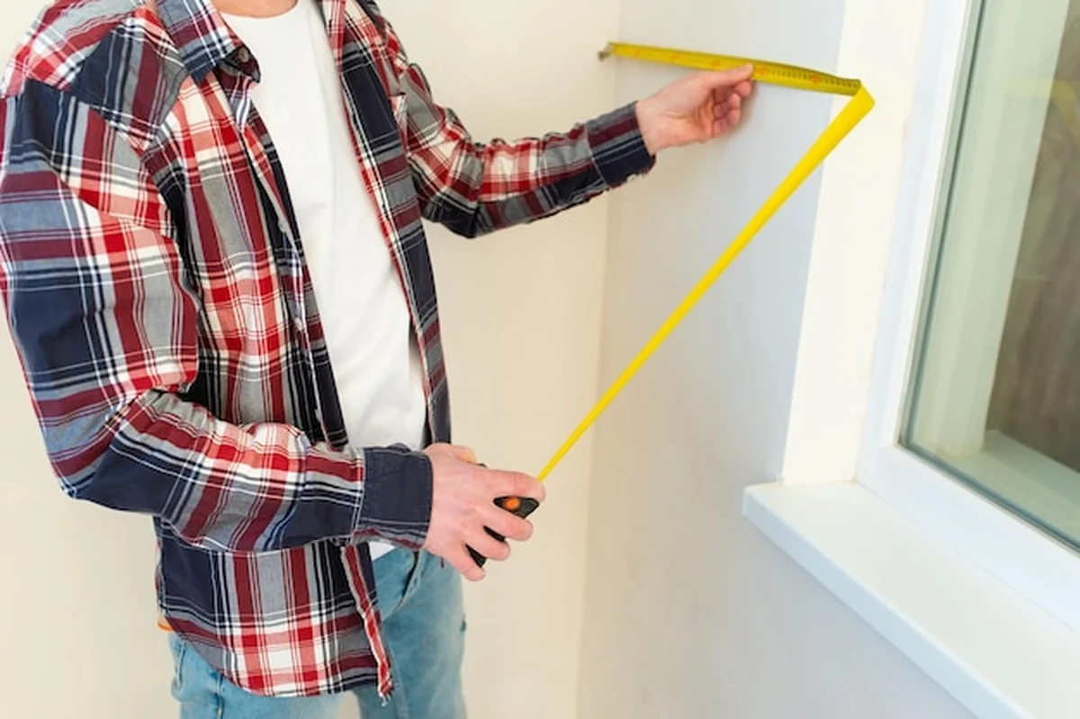 Budowniczy mierzy szerokość taśmą mierniczą