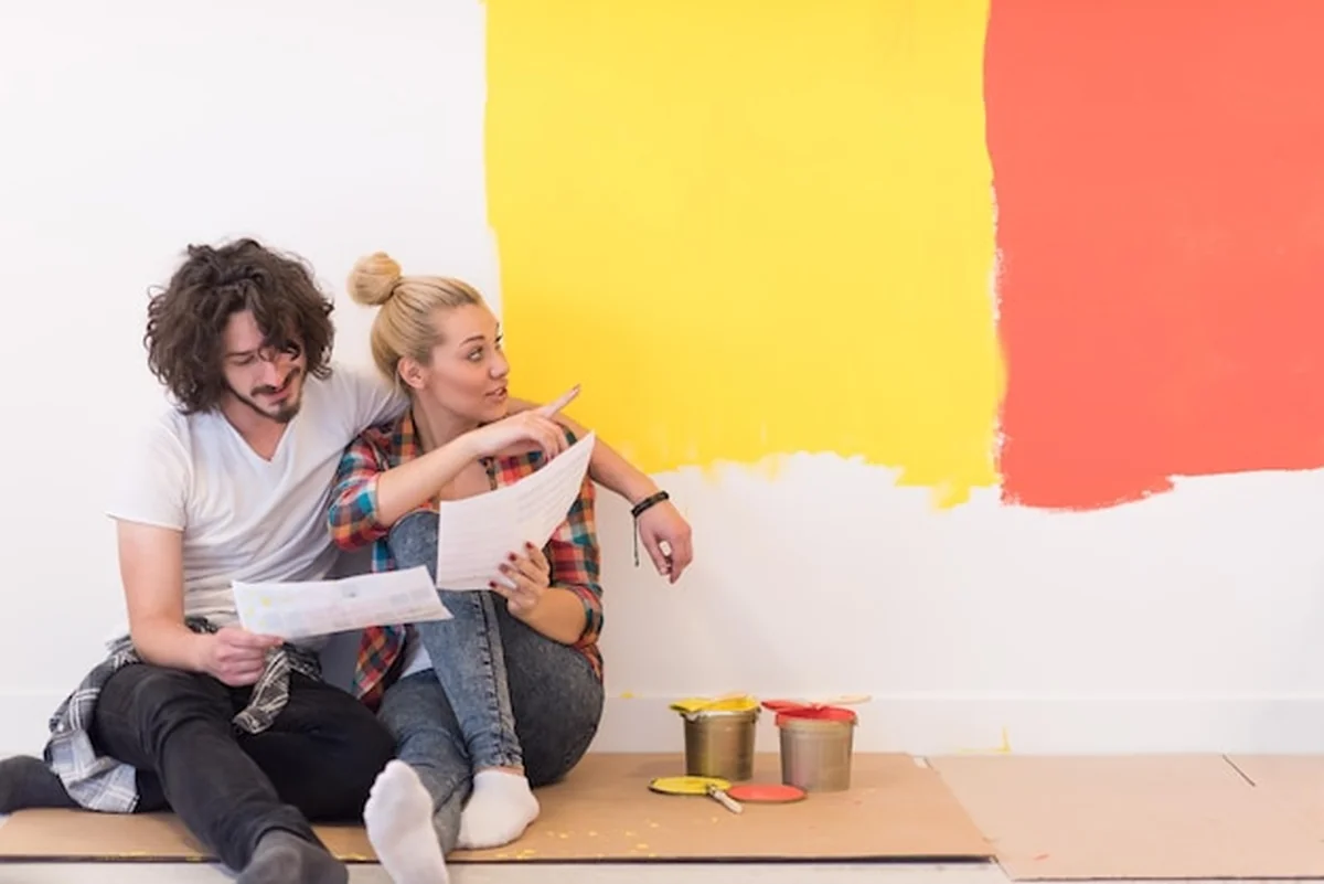 Młoda para relaksuje się po malowaniu pokoju w nowym domu