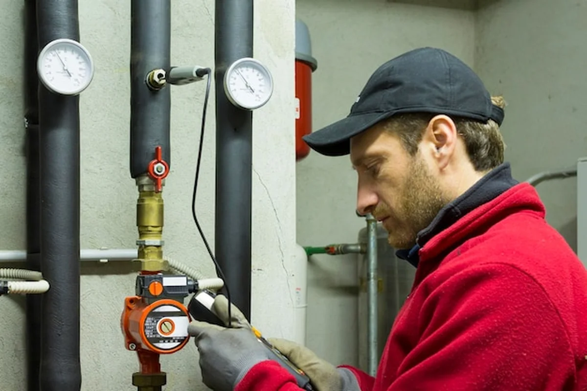 Hydraulik trzymający urządzenie pomiarowe podczas naprawy układu grzewczego